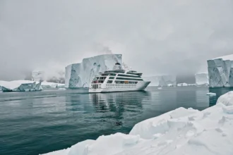 Navire de croisière Ponant naviguant entre les icebergs en Arctique sur une mer glacée turquoise