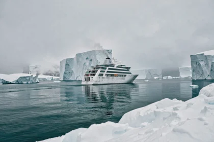 Navire de croisière Ponant naviguant entre les icebergs en Arctique sur une mer glacée turquoise